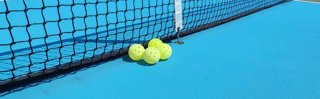 iam-Pickleball.com :   Yellow pickleballs on a blue court. High-quality outdoor pickleball balls for smooth and consistent play.