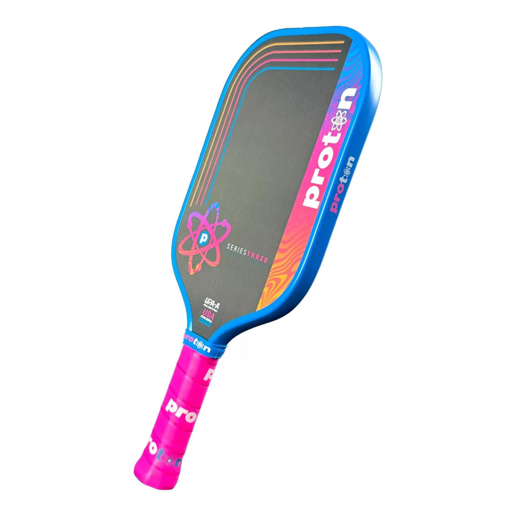 A Proton Series Three - Project Flamingo Elongated 13mm Pickleball Paddle with blue edge guard, available from IamRacketsports.com, online and in-store, Miami USA, worldwide shipping.
