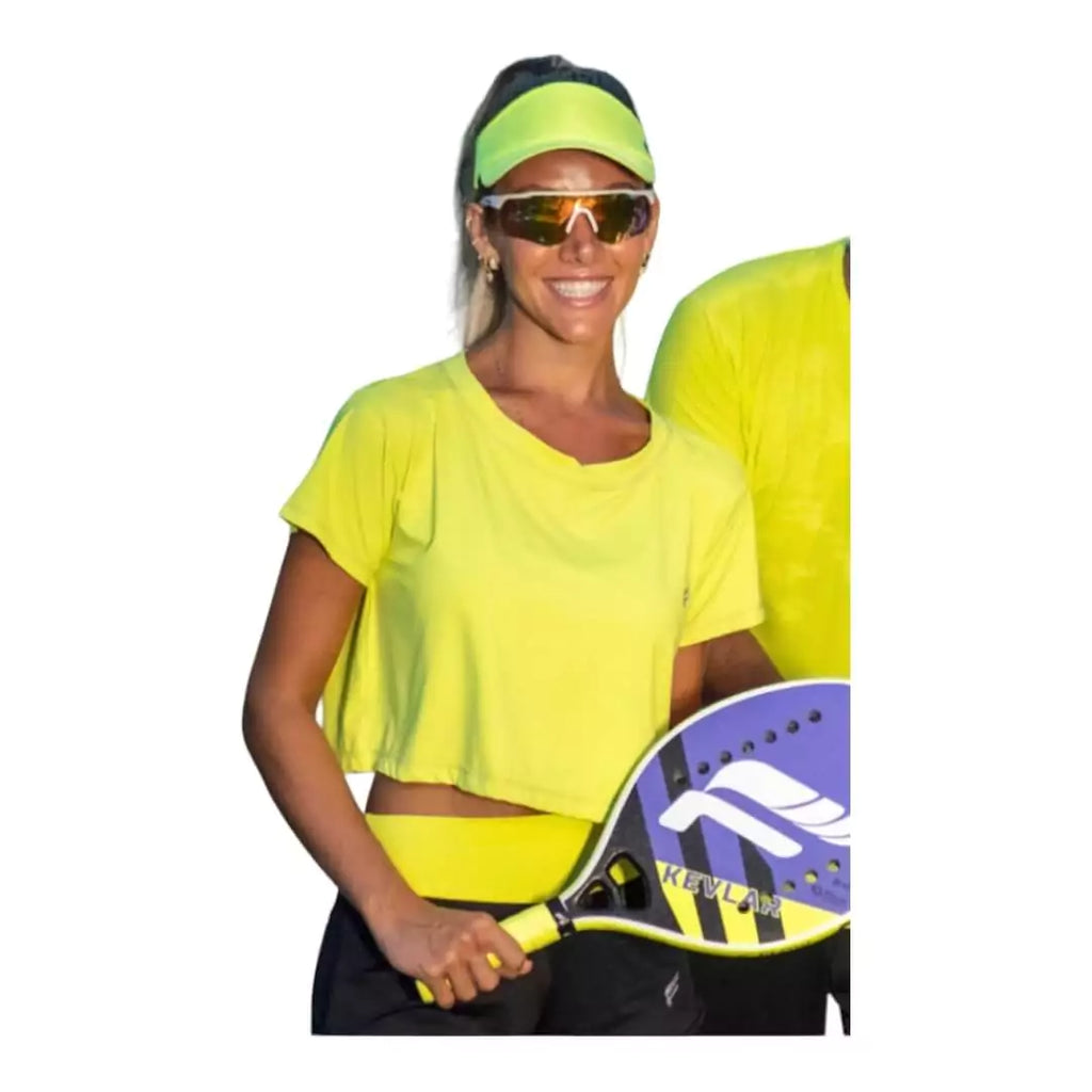 SPORT:BEACH TENNIS. Shop Flow Beach tennis at "iamracketsports.com". Female model, wearing a green  Flow VENICE Cropped T-Shirt.