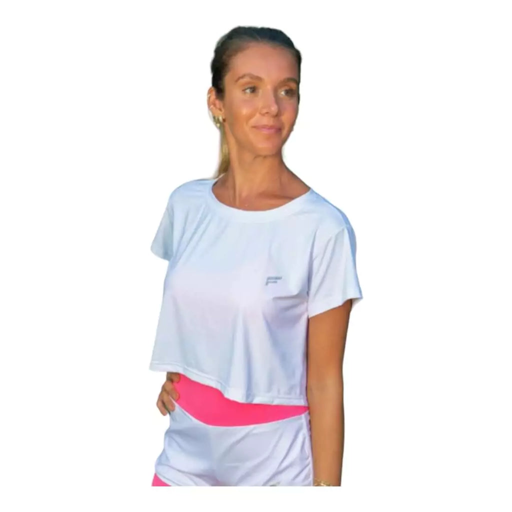 SPORT:BEACH TENNIS. Shop Flow Beach tennis at iamBeachTennis.com. Female model, standing sideways wearing white Flow VENICE Cropped T-Shirt.