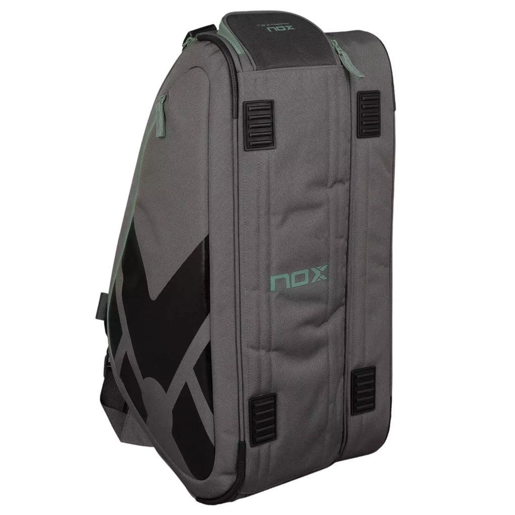 A standing, gray and green Nox AT10 TEAM Padel Racket Bag, available from "iamracketsports.com", Miami shop.