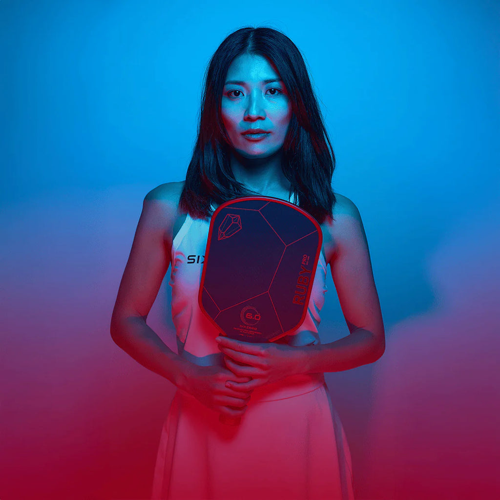 A women holding a Six Zero RUBY PRO 14mm PickleBall Paddle,  available from IamRacketsports.com, online and in-store, Miami USA, worldwide shipping.