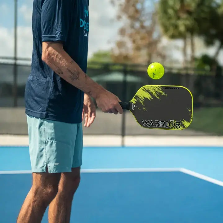 Shop Diadem Pickleball at iamracketsports, Miami, FL, USA. Professional rated, 19 mm, Poly Honeycomb core, carbon face with grit paint and medium high balance point, Diadem Warrior v2 pickleball paddle on court with player.