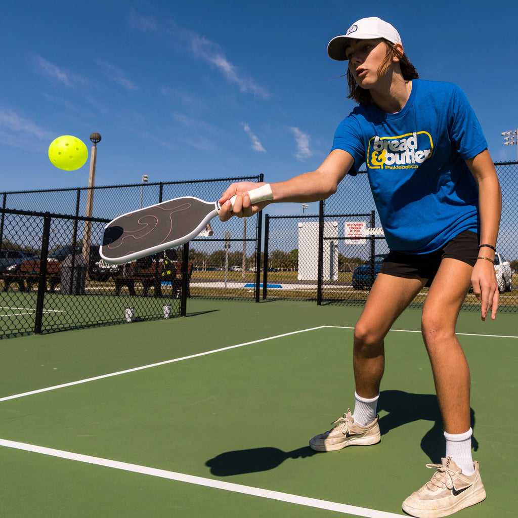 A player on court with a white Bread & Butter FILTH 16mm 2024 Elongated Pickleball Paddle, available at iamracketsports.com.