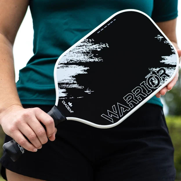 Diadum Warrior v2 pickleball Paddle, at iamBeachTennis.com online Boutique store.Professional rating, 19 mm, Poly Honeycomb core, carbon face with grit paint and medium high balance point, vertical ,face on profile. in winter white held by pickleball player